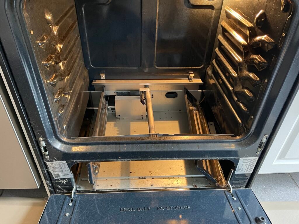 GE oven disassembled with bottom cover, door, and drawer removed prepped for professional deep cleaning