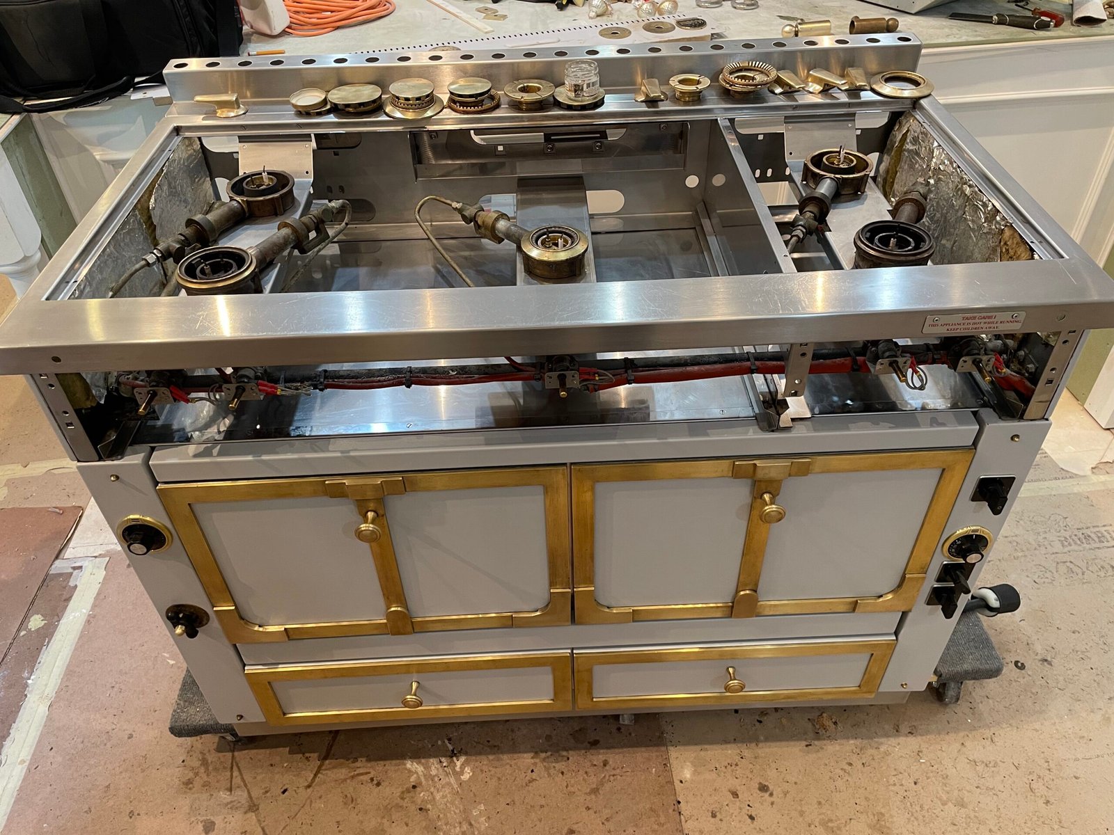 La Cornue Château double‑oven range fully disassembled in a New York City residence, displaying cleaned components, polished metal accents, and degreased stainless‑steel panels during a specialized restoration service.