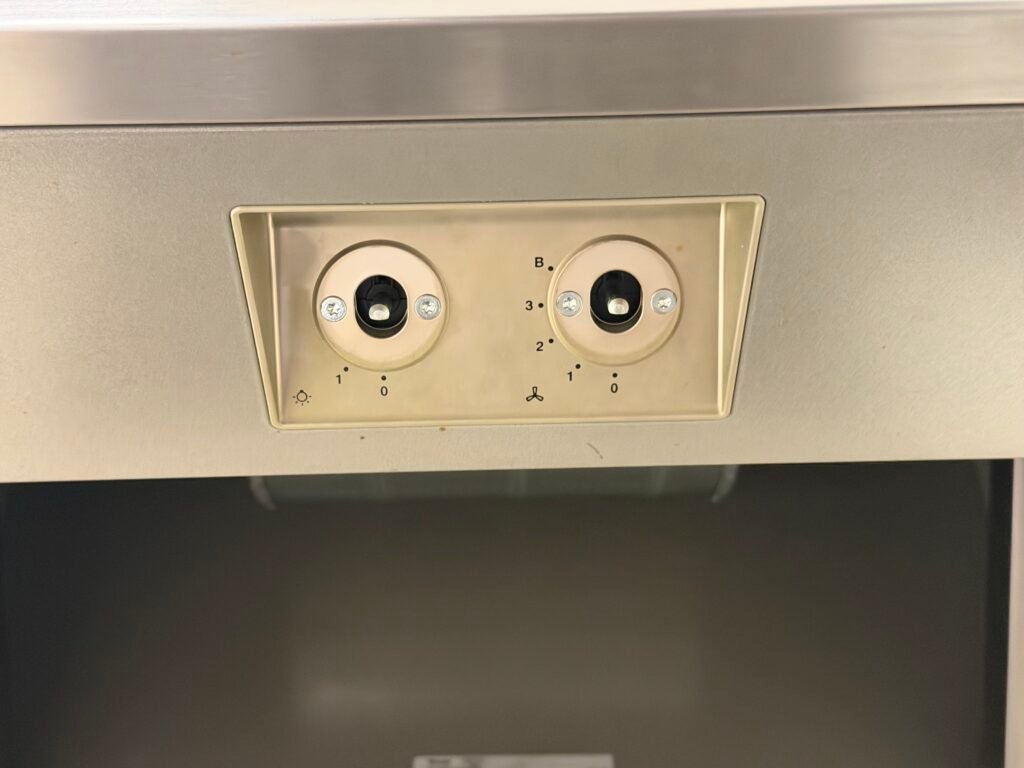 echnician carefully detailing stainless steel control panel of range hood