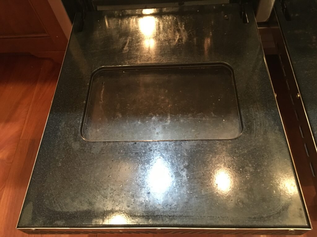 Baked on grease on oven door and glass before OvenPal's signature cooking range deep cleaning