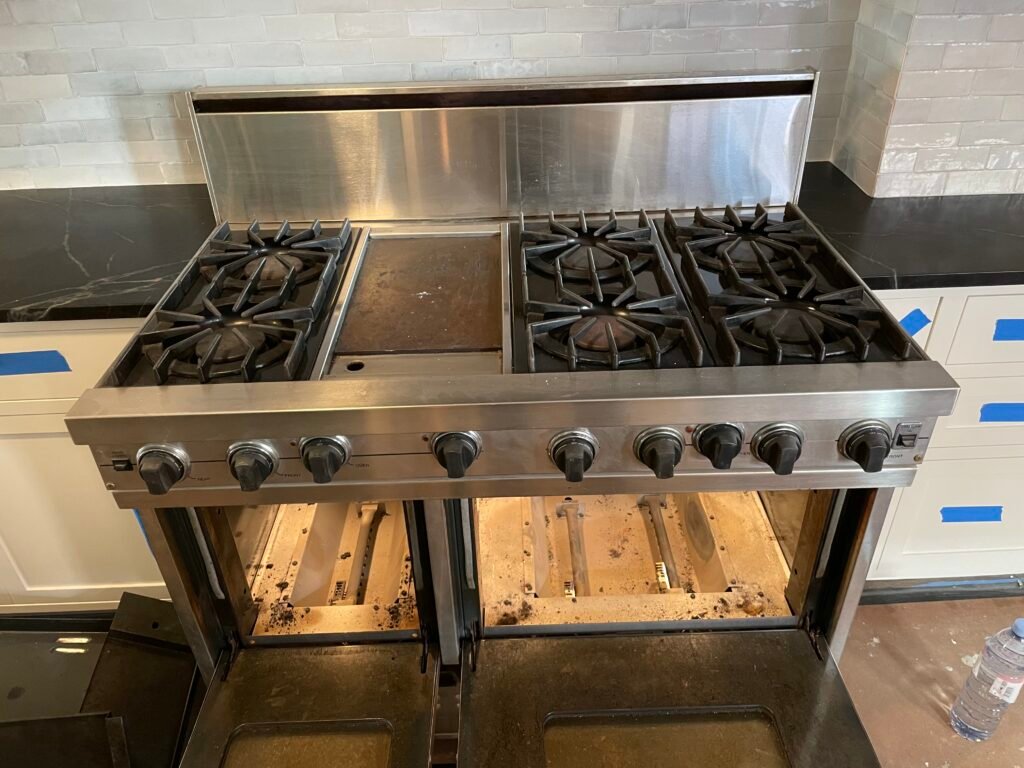 Viking professional range with heating elements exposed after disassembly, doors and glass covered in baked-on grease before deep cleaning