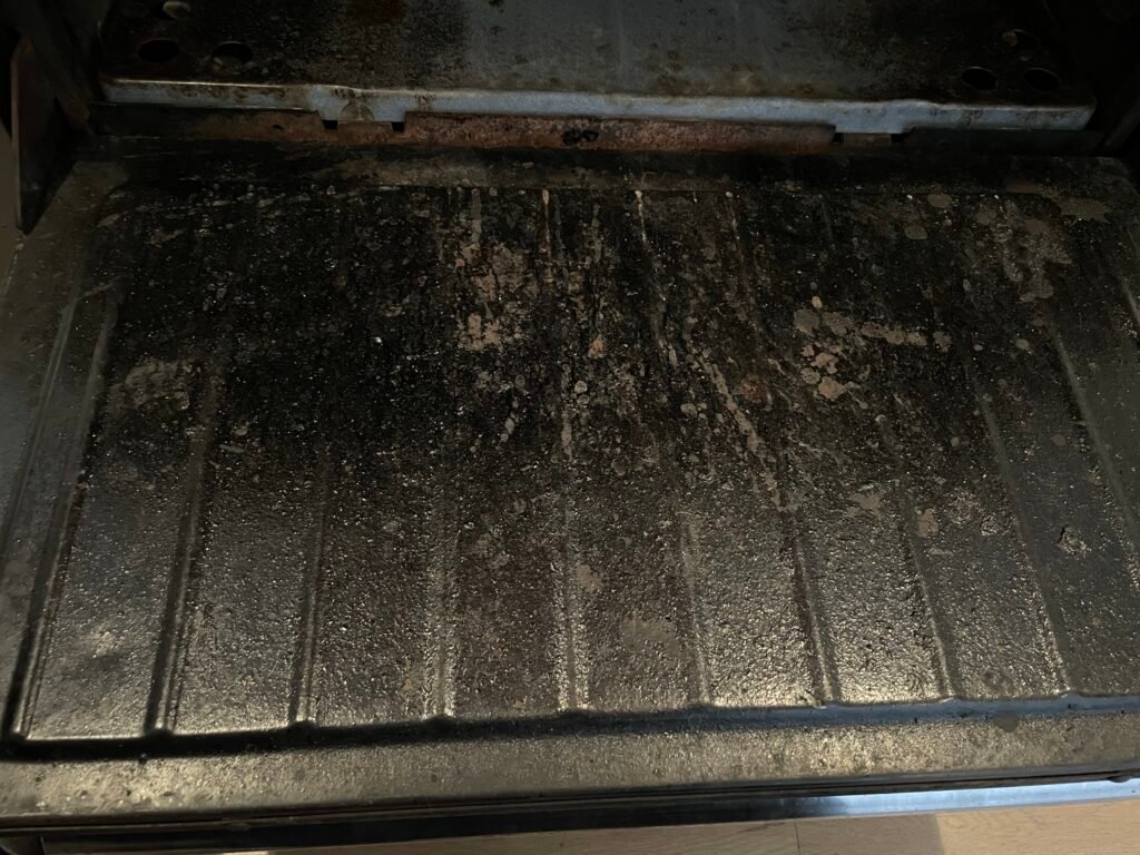 Grease‑covered door of an oven before professional deep cleaning and detailing service.