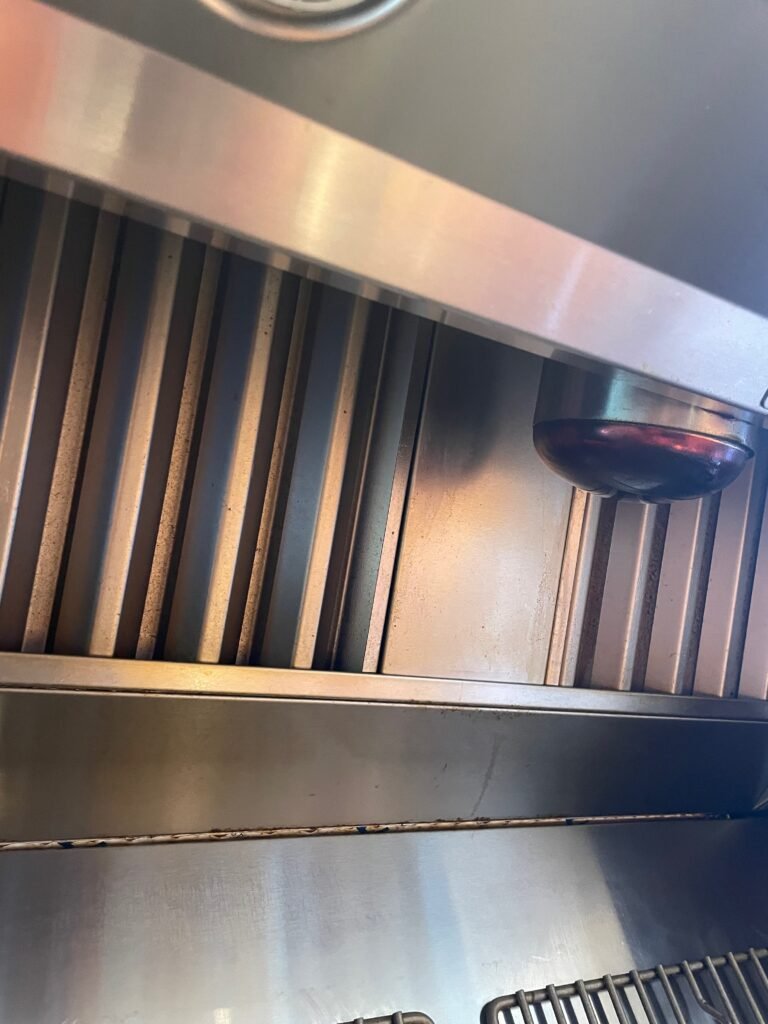 Grease buildup on BlueStar hood baffles and heating lamp before expert range hood cleaning