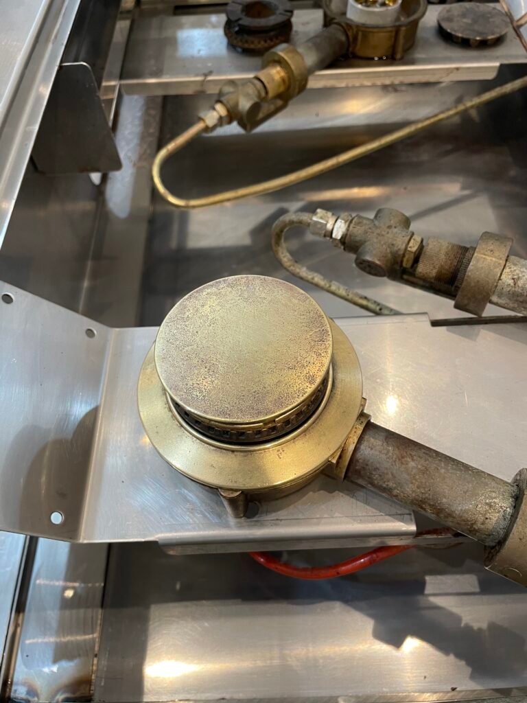 Brass burners, burner rings, and burner caps after professional oven deep cleaning, restoration and detailing — spotless shine and renewed finish.