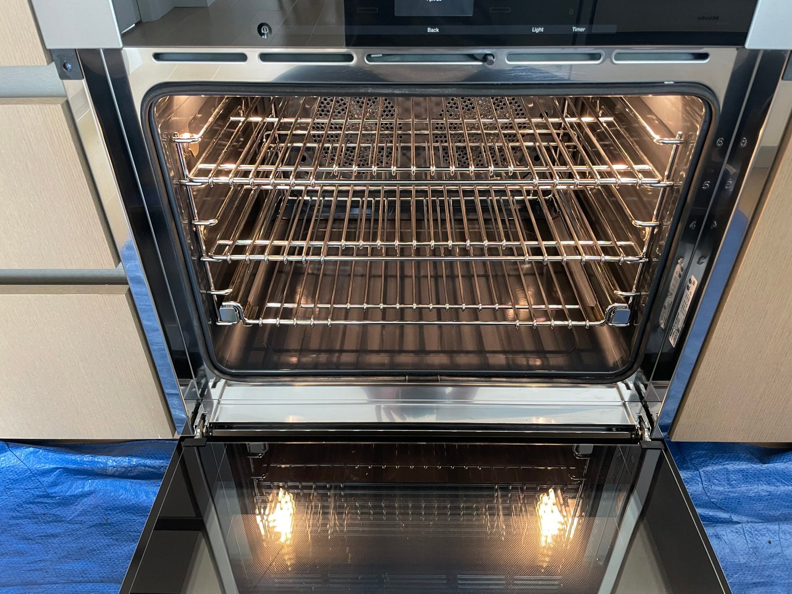 Interior view of a freshly deep-cleaned Miele built-in electric oven in NYC, highlighting the spotless PerfectClean coating, fan element, and stainless steel racks.
