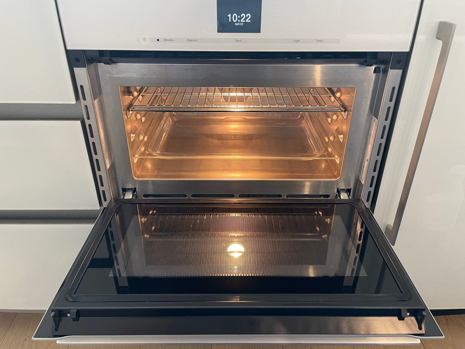 A showroom-ready Miele built-in oven after professional restoration, featuring polished glass and detailed racks in a modern NYC apartment.