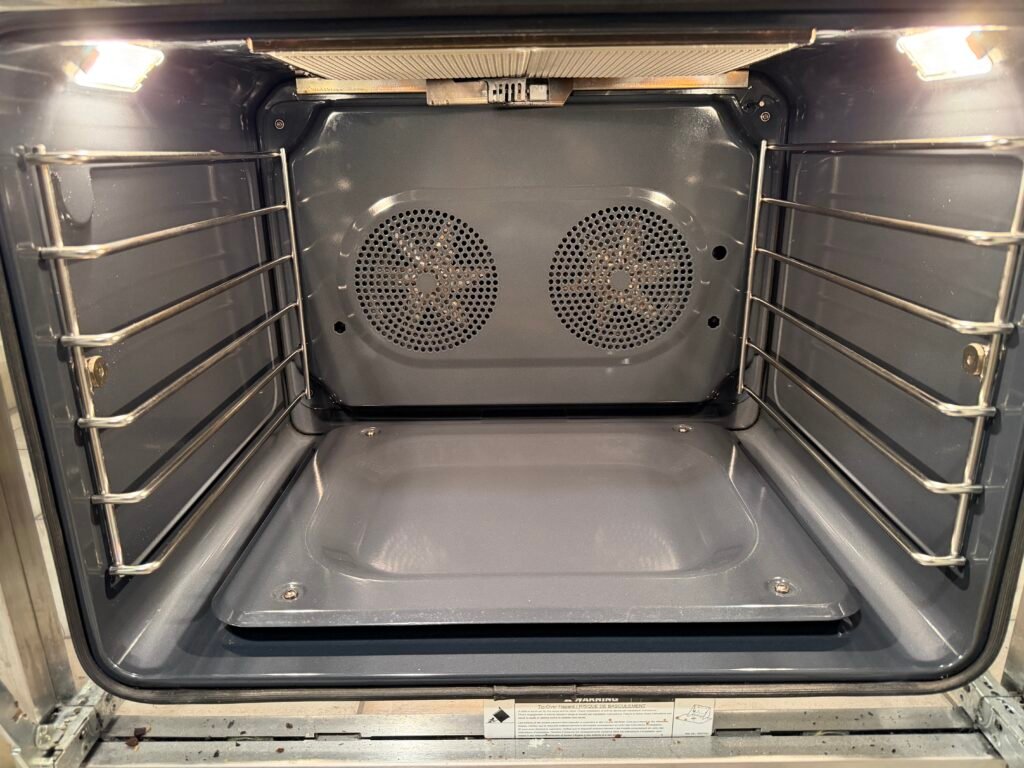 NYC appliance cleaning specialist performing deep interior sanitation on a Miele gas range with non‑toxic degreasing, carbon removal, glass cleaning, and microfiber polishing as part of premium multi‑appliance detailing