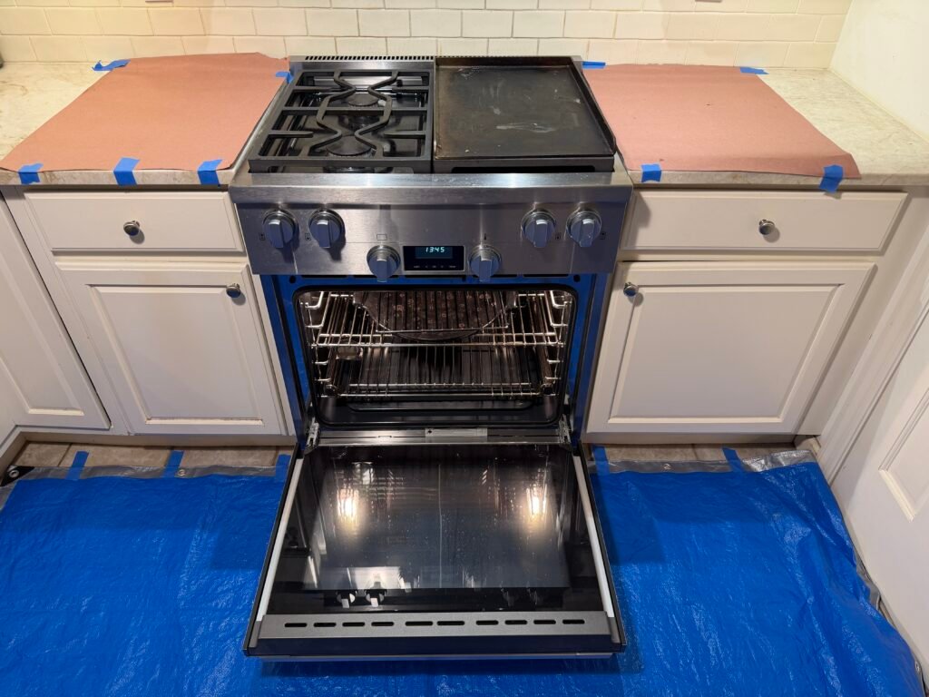 NYC luxury appliance technician inspecting a Miele gas range, reviewing condition, testing functionality, identifying buildup, applying protective coverings, and confirming client concerns before cleaning or restoration
