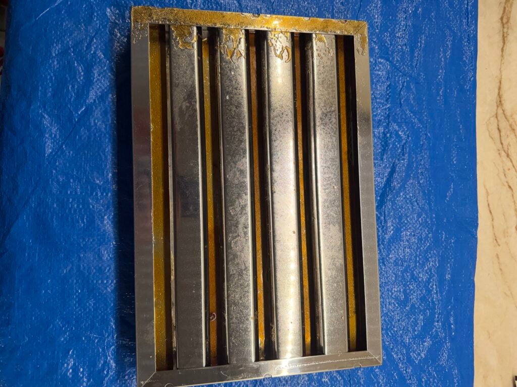 IMG_0762 Stainless‑steel Viking hood baffles with heavy grease saturation, darkened surfaces, and airflow‑blocking residue across the baffle channels.